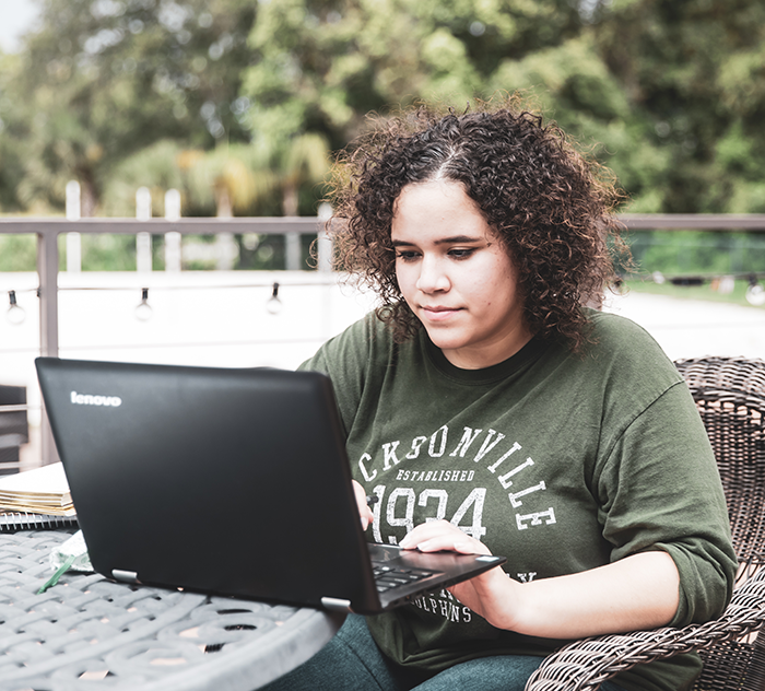 Student on the JU green browsing on her laptop.